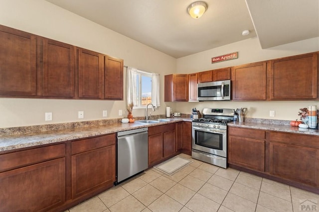 kitchen with brown cabinets, light countertops, appliances with stainless steel finishes, light tile patterned flooring, and a sink