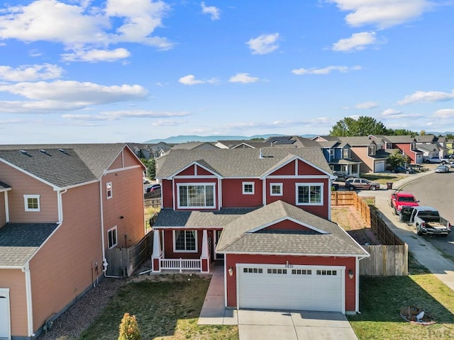 traditional-style home featuring a shingled roof, concrete driveway, fence, a garage, and a residential view