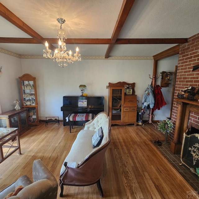 living room with a fireplace, wood finished floors, beam ceiling, and a notable chandelier