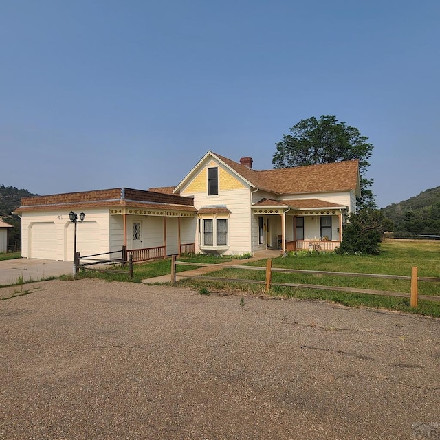 view of front of property featuring concrete driveway, a chimney, an attached garage, and fence