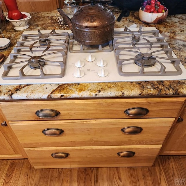 room details with brown cabinetry, cooktop, and dark stone countertops