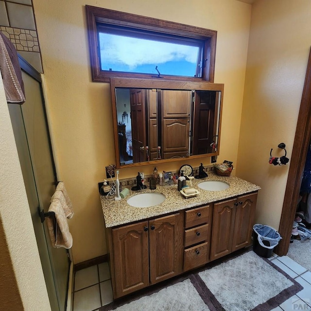 bathroom with tile patterned flooring, a sink, baseboards, and double vanity