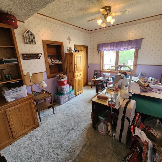 office featuring wallpapered walls, a ceiling fan, wainscoting, light colored carpet, and a textured ceiling