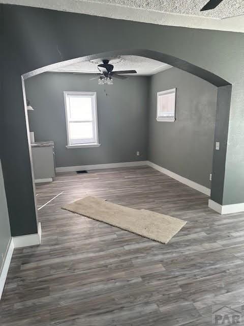 interior space featuring arched walkways, plenty of natural light, and a ceiling fan