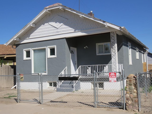 view of front of home with a fenced front yard, a gate, and stucco siding