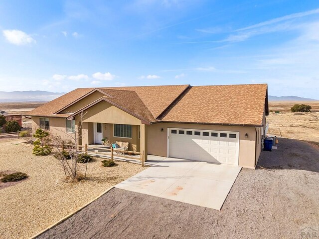 single story home with a garage, a mountain view, concrete driveway, and stucco siding