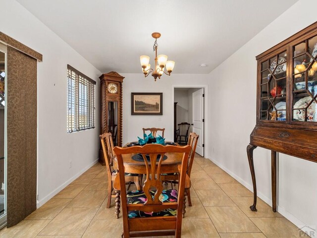 dining area with light tile patterned floors, baseboards, and a chandelier