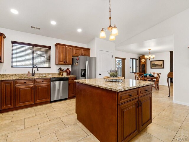 kitchen with a kitchen island, decorative light fixtures, an inviting chandelier, stainless steel appliances, and a sink