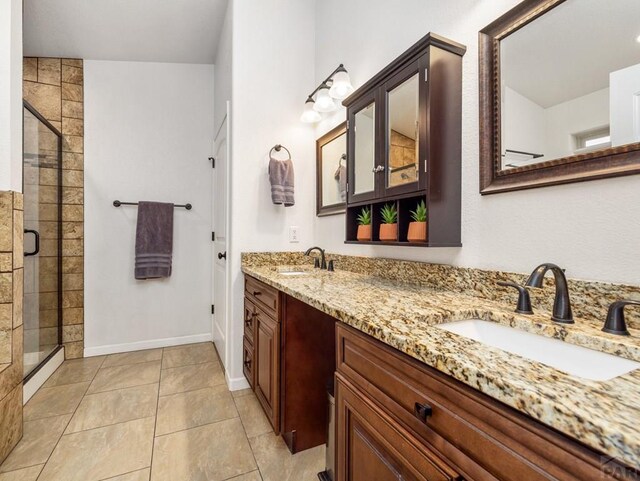 bathroom with tile patterned floors, a sink, a shower stall, and double vanity