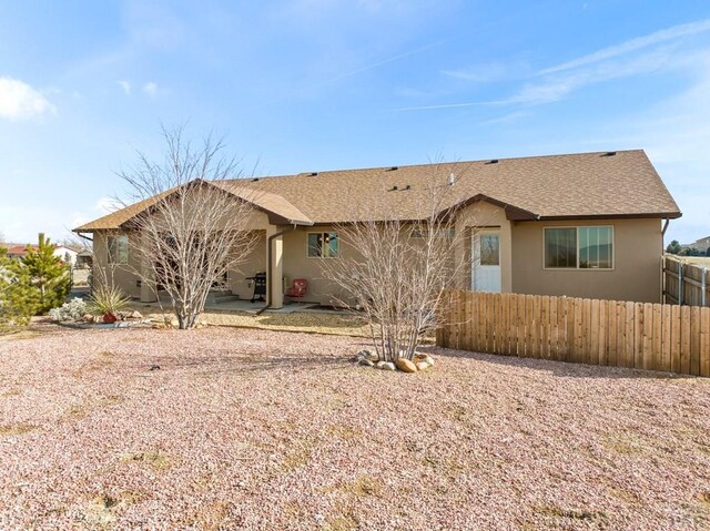 view of front of house featuring a shingled roof, fence, and stucco siding