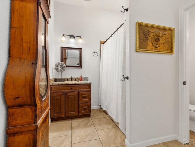 bathroom with toilet, tile patterned flooring, and vanity