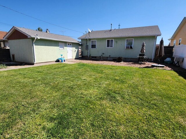 back of house with a lawn, fence, and stucco siding