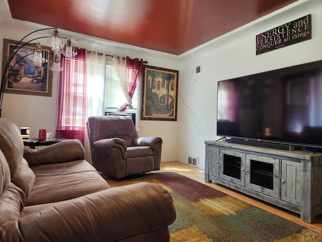 living area featuring visible vents, an inviting chandelier, and wood finished floors