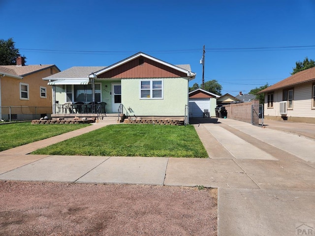 view of front of house with an outbuilding, a detached garage, a porch, fence, and a front lawn