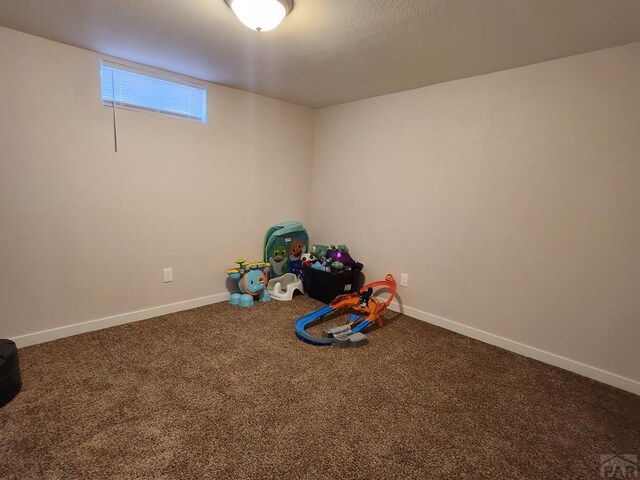 game room with a textured ceiling, carpet floors, and baseboards