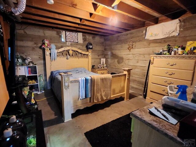 bedroom with wooden walls and concrete floors