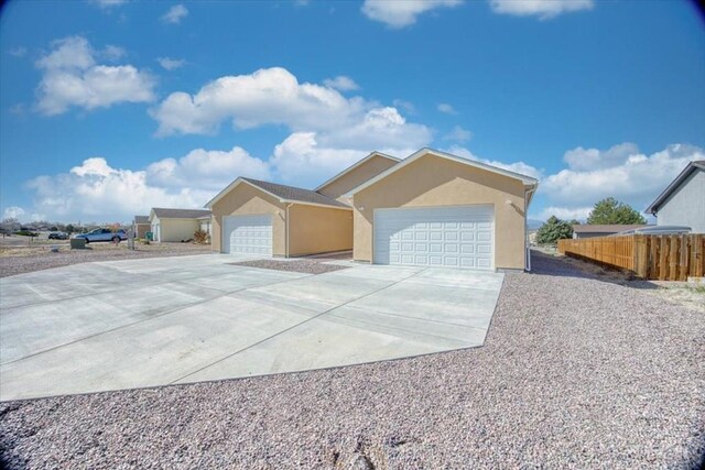 ranch-style home featuring a detached garage, fence, an outbuilding, and stucco siding