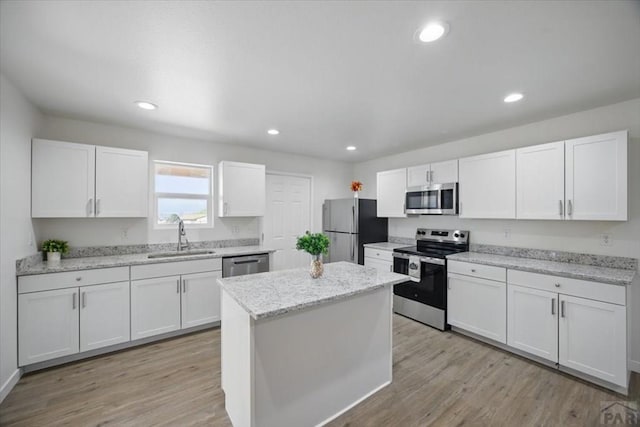 kitchen featuring a sink, a center island, stainless steel appliances, white cabinetry, and light wood-type flooring
