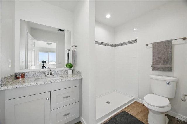 bathroom featuring vanity, toilet, baseboards, a shower stall, and wood finished floors