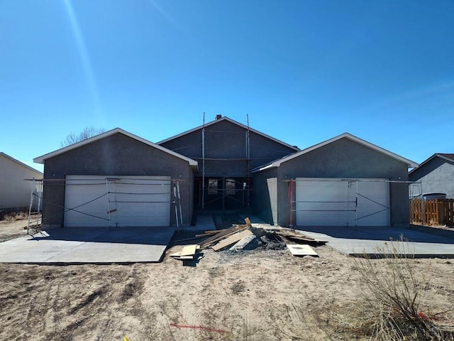 view of front facade with an attached garage, fence, and stucco siding