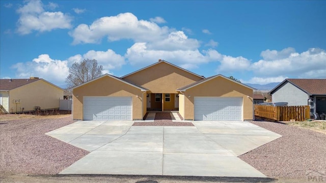 ranch-style home featuring a garage, fence, stucco siding, and driveway