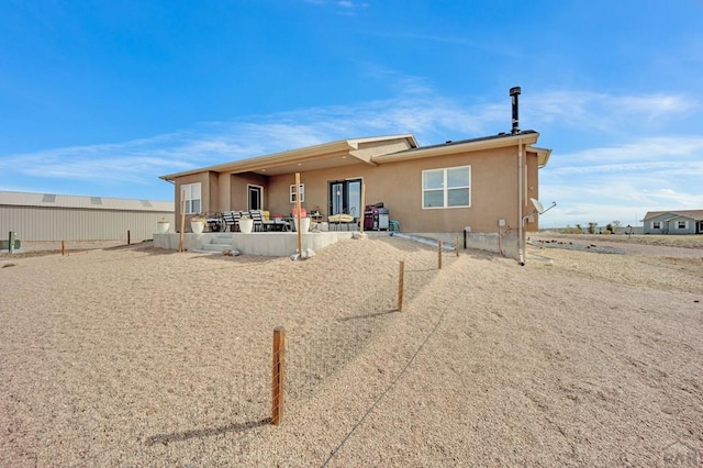 rear view of property featuring a patio area, stucco siding, and fence