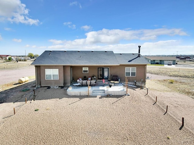 back of property with an outdoor living space, stucco siding, roof with shingles, and a patio
