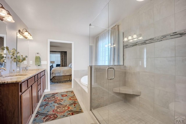 ensuite bathroom featuring double vanity, a shower stall, a garden tub, and a sink