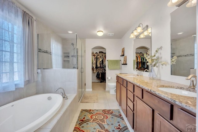 bathroom with a shower stall, a garden tub, tile patterned floors, a sink, and a spacious closet