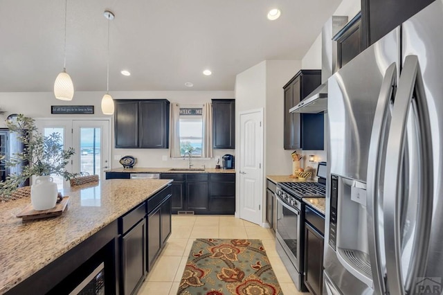 kitchen featuring a wealth of natural light, light stone countertops, stainless steel appliances, and a sink