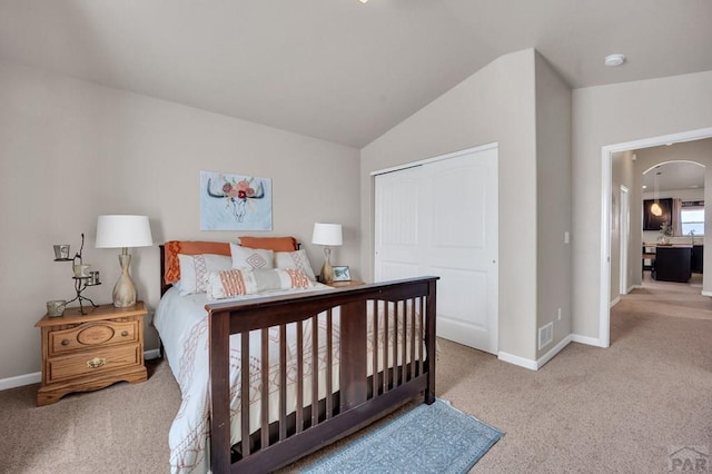 bedroom featuring arched walkways, lofted ceiling, carpet flooring, and baseboards