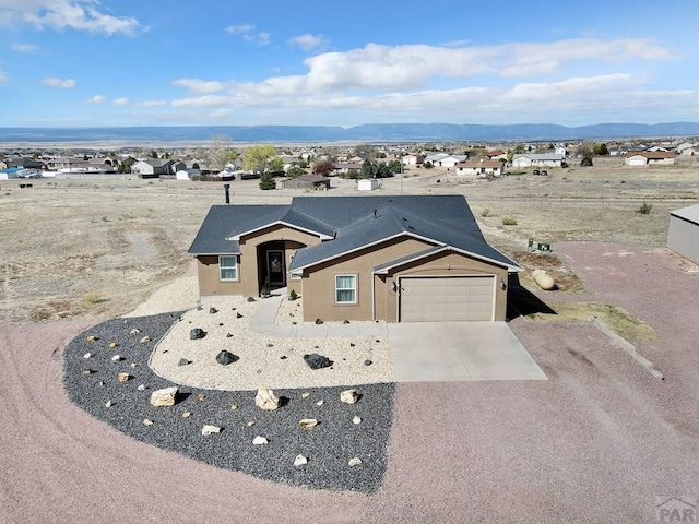 view of front of property featuring an attached garage, stucco siding, a mountain view, and concrete driveway