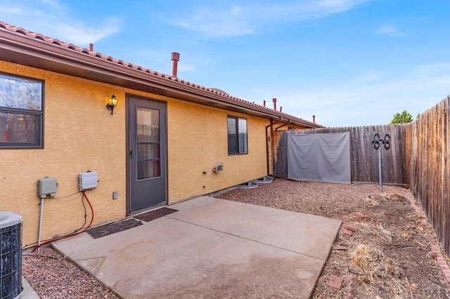 rear view of house featuring a fenced backyard, a patio, central AC, and stucco siding