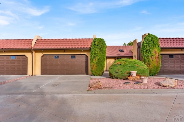 view of front of property with concrete driveway, a tile roof, and stucco siding