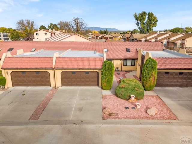 view of front of house featuring stucco siding, a mountain view, a residential view, driveway, and a tiled roof