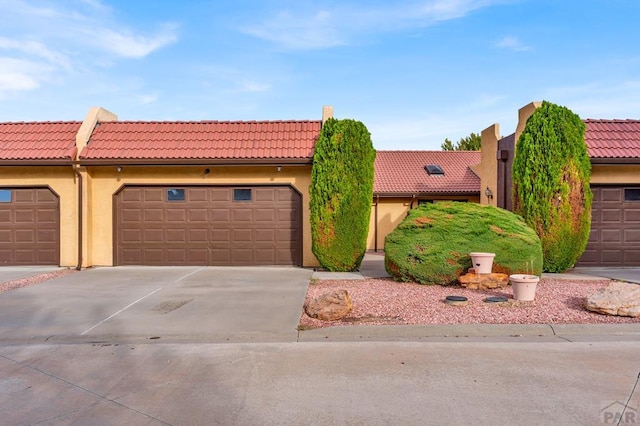 view of front of home featuring driveway, a tile roof, and stucco siding