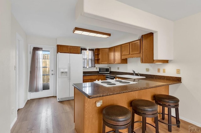 kitchen featuring brown cabinets, open shelves, appliances with stainless steel finishes, a sink, and a peninsula