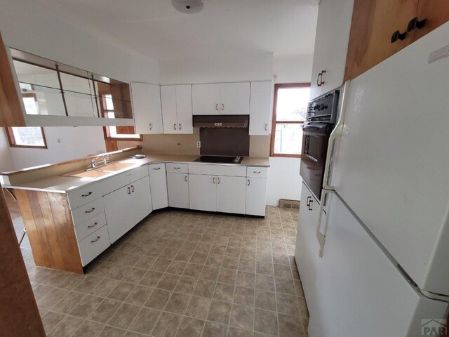 kitchen with light countertops, white cabinetry, under cabinet range hood, and black appliances