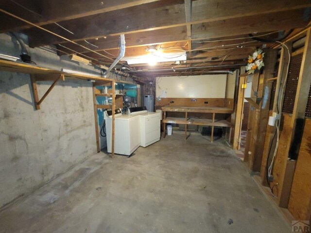 unfinished basement featuring water heater and washing machine and dryer