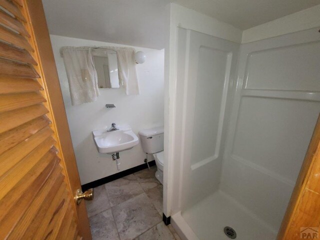 full bathroom featuring toilet, a shower stall, baseboards, and a sink