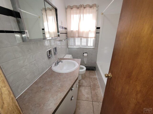 bathroom with shower / washtub combination, tile walls, toilet, vanity, and tile patterned flooring