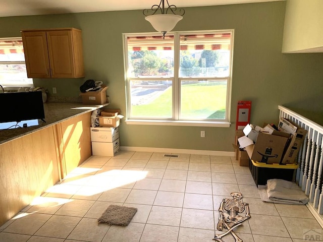 kitchen with decorative light fixtures, light tile patterned floors, visible vents, dark stone counters, and baseboards