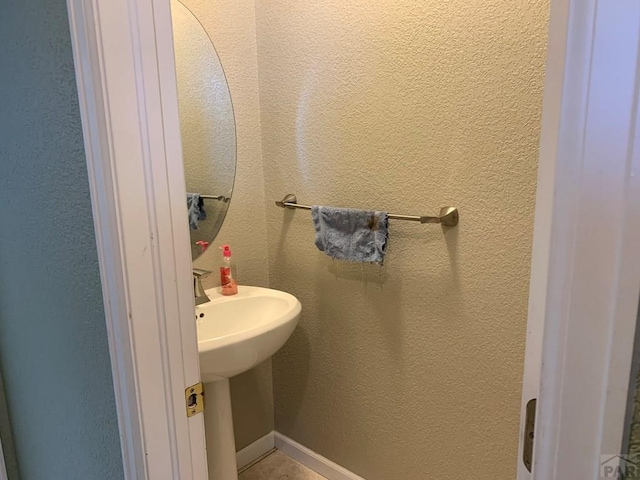 bathroom featuring baseboards, a sink, and a textured wall