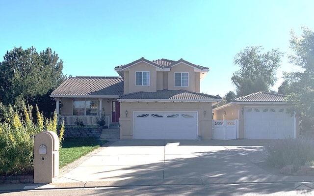 traditional-style house with concrete driveway, a tiled roof, covered porch, fence, and stucco siding