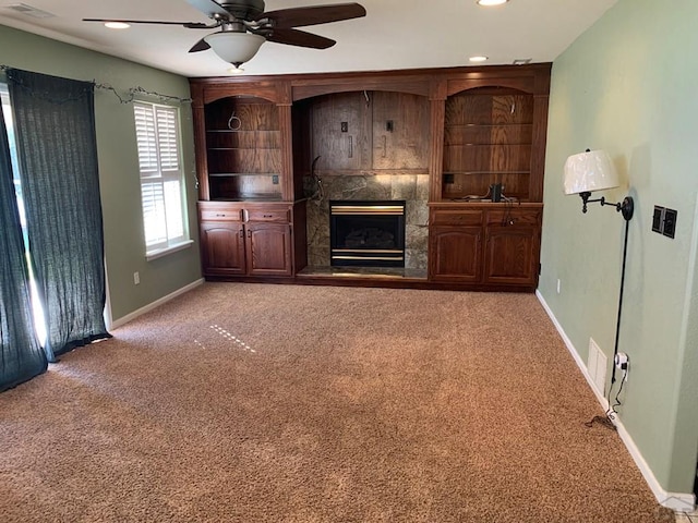 unfurnished living room featuring ceiling fan, carpet, baseboards, and a fireplace with raised hearth