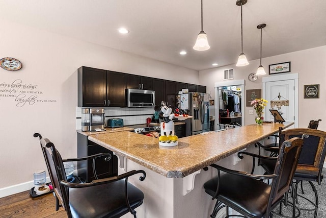 3327 Lions Pride Ln, Pueblo, CO 81005 - kitchen with stainless steel appliances, backsplash, wood finished floors, a breakfast bar area, and baseboards