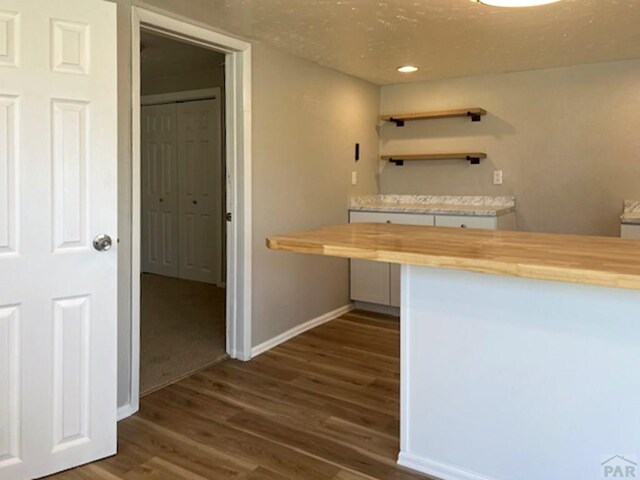 kitchen featuring baseboards, dark wood-style floors, wood counters, open shelves, and recessed lighting