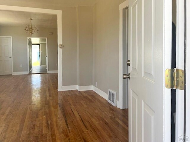 unfurnished room with dark wood-style floors, visible vents, and baseboards