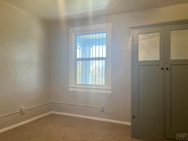 carpeted empty room with baseboards