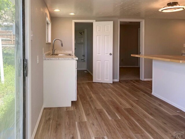 kitchen with baseboards, dark wood finished floors, light countertops, white cabinetry, and a sink